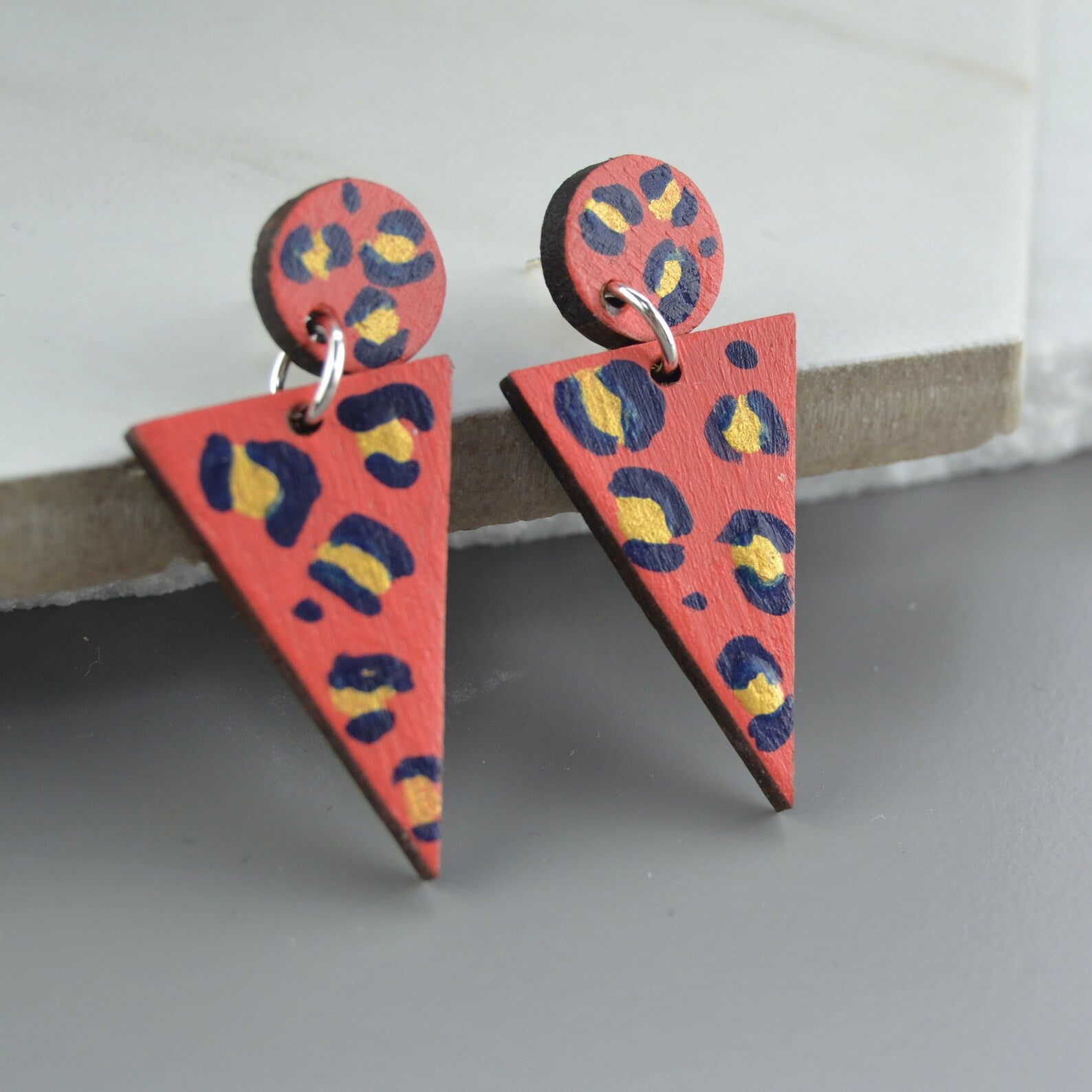 Triangular earrings with a colorful pattern on a gray surface